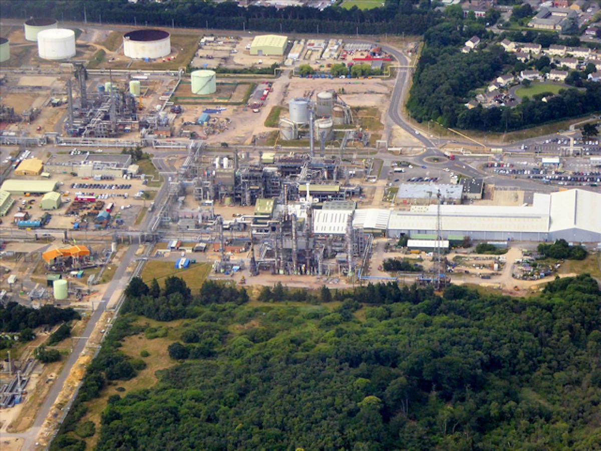 An aerial view of the Fawley oil refinery and petrochemicals plant in Hampshire, England, showing storage tanks, processing towers, and interconnected pipelines.